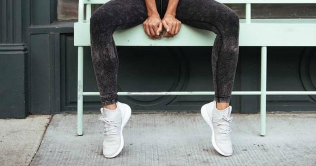 woman sitting on bench in athletic pose wearing Reebok shoes