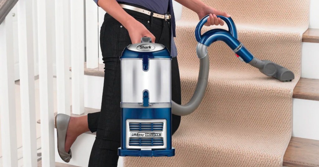 woman vacuuming carpet on stairs with shark liftaway deluxe in blue