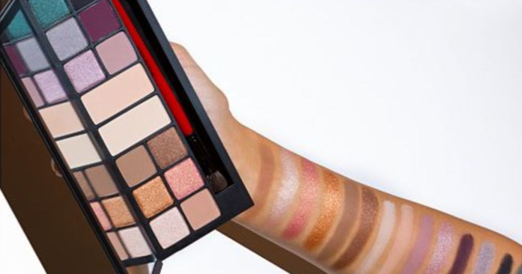 Hand with eye shadow swatches on arm holding Smashbox The Love Edit: Romantic Eye Shadow Palette