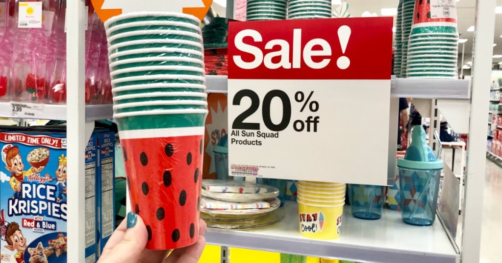 Sun Squad paper cups in watermelon print held up in front of a sale sign