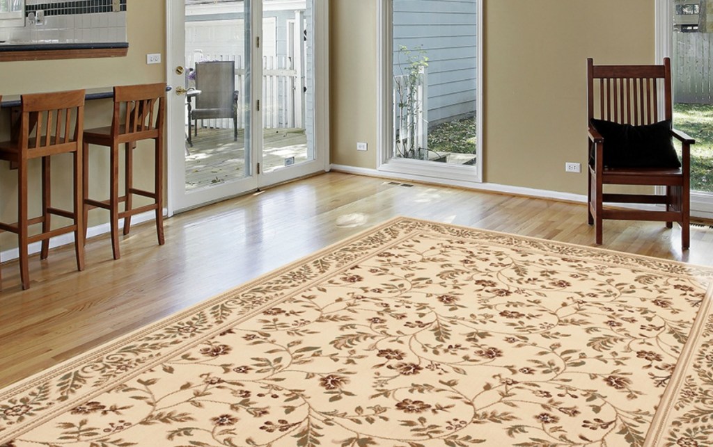 cream and flowered rug in living room with hard wood floor, and chairs 