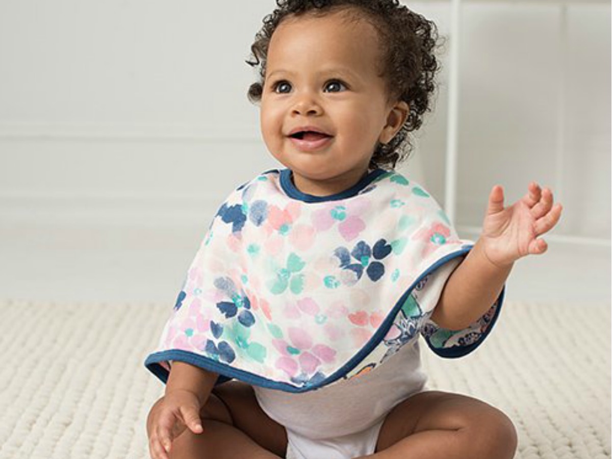 baby sitting on floor with burp cloth