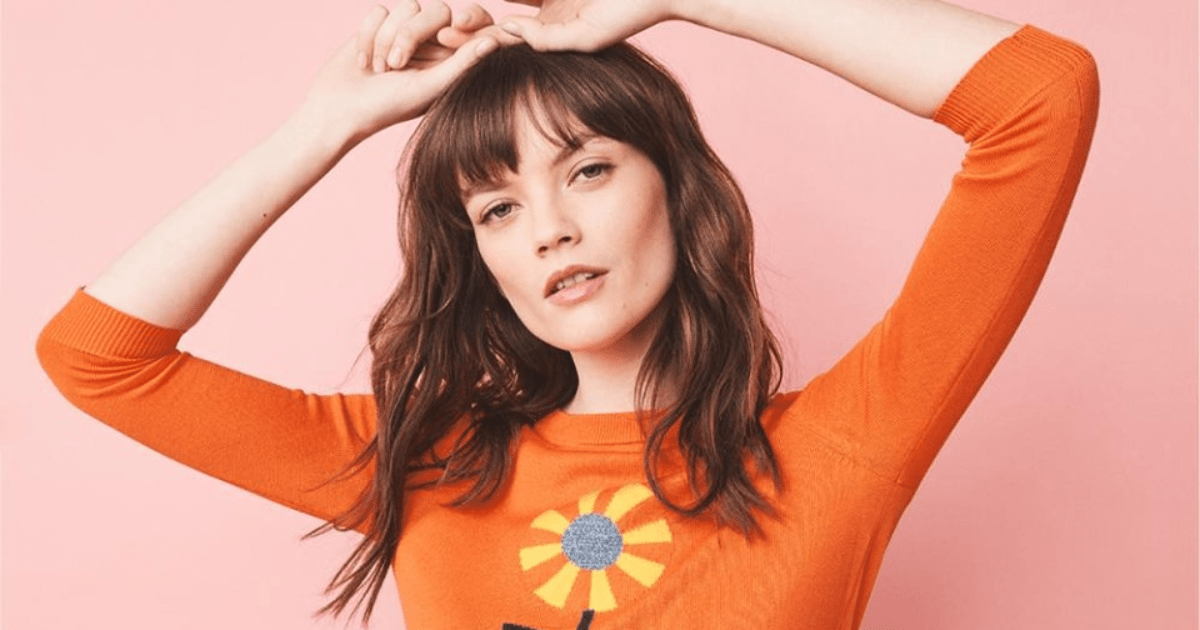 woman wearing an orange shirt with a flower