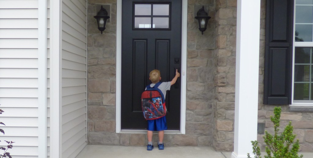 boy with Spiderman backpack opening black door