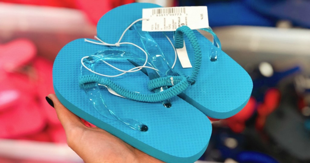 hand holding pair of blue flip flops