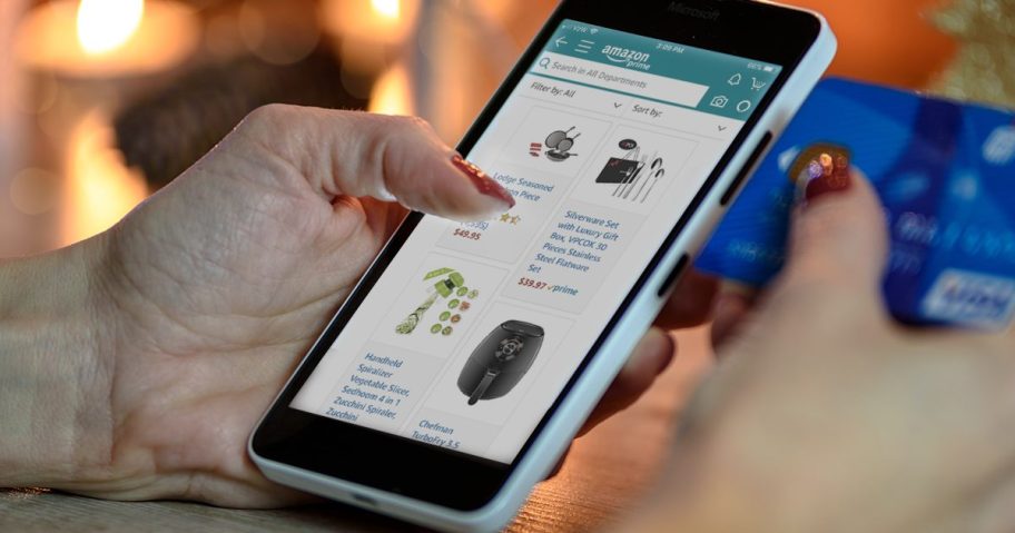 scrolling amazon on phone with credit card in hand such as the Amazon visa, one of the amazon prime perks