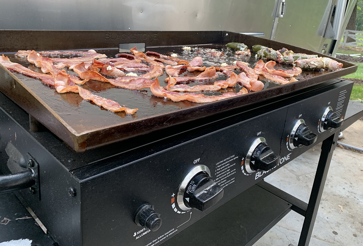 outdoor griddle cooking bacon and jalapeno poppers