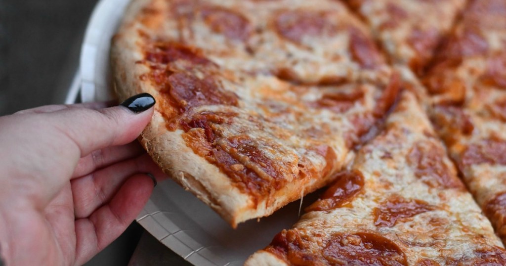 hand grabbing pizza slice from pizza tray