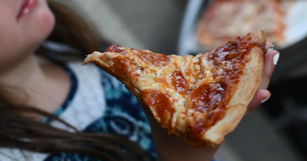 girl lifting up pizza slice about to eat