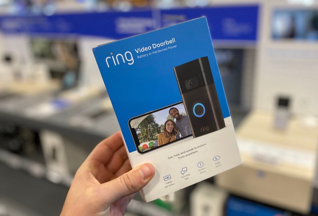 hand holding a ring doorbell in blue box in store