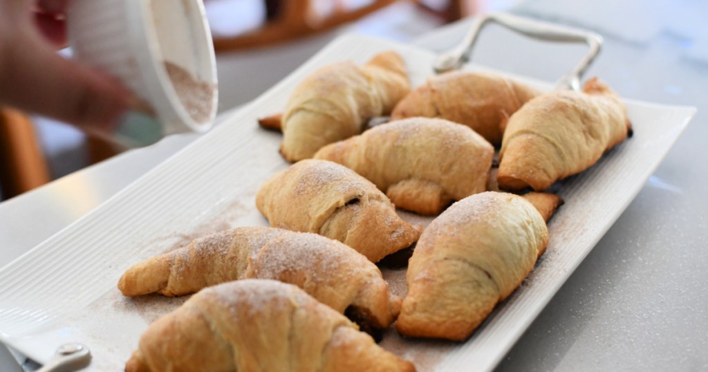 sprinkling cinnamon sugar over nutella crescent rolls