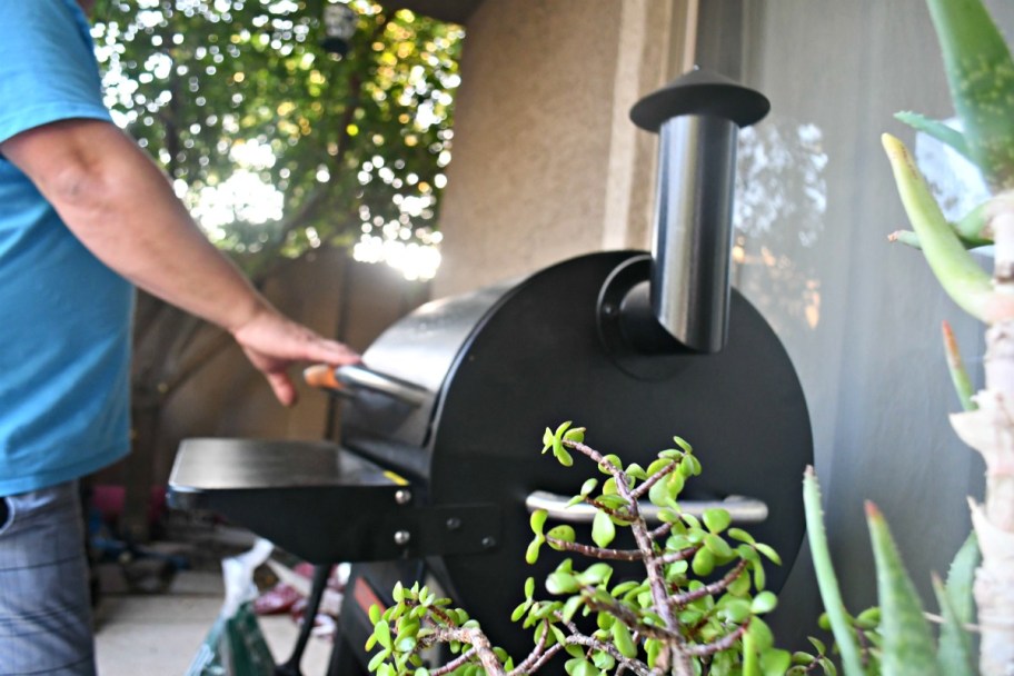 opening the lid of the Traeger smoker in backyard