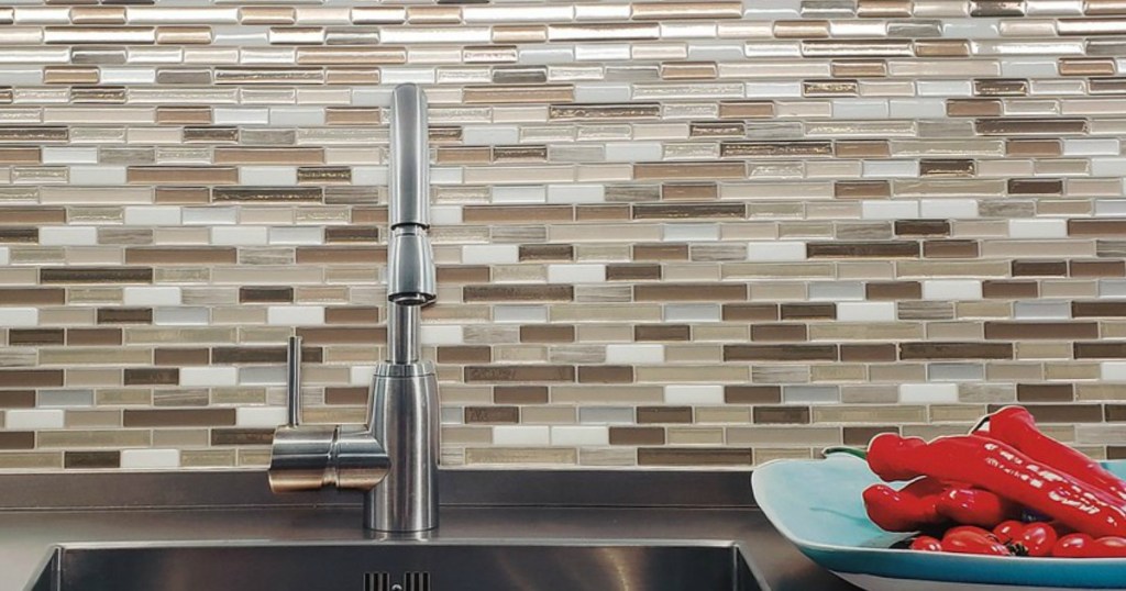 Kitchen sink with mosaic backsplash and plate of peppers on counter