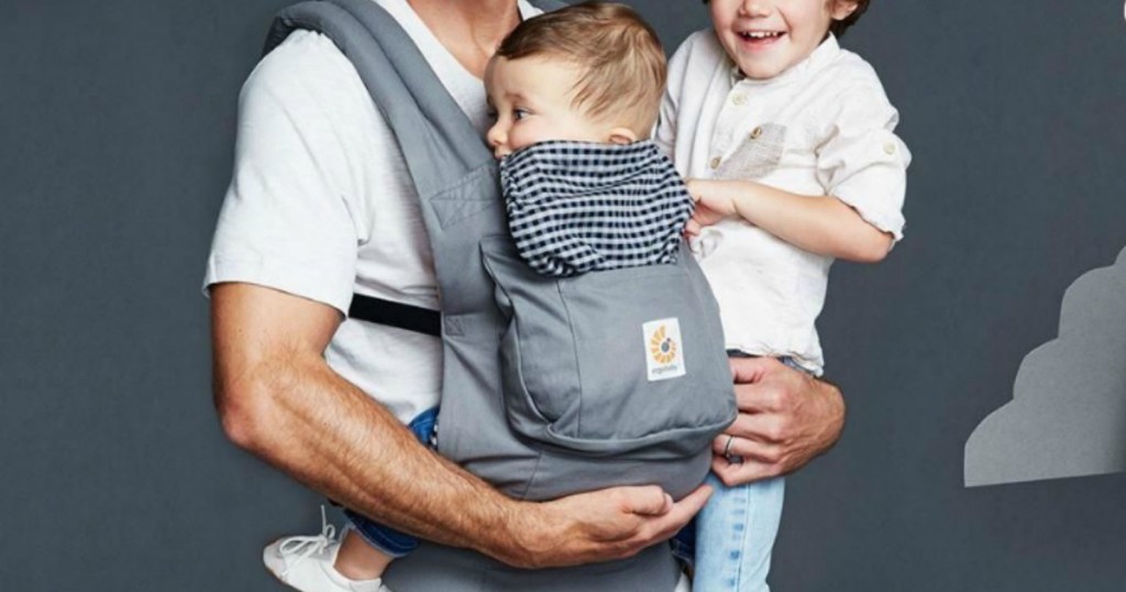 Baby being worn by dad in a gray and plaid baby carrier