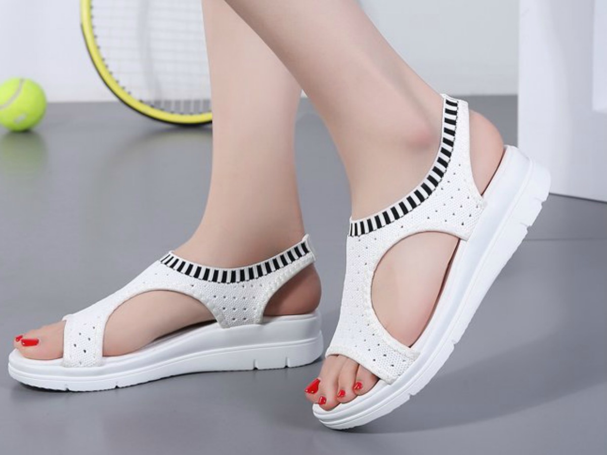 Woman wearing Konhill Sandals in white next to tennis racket