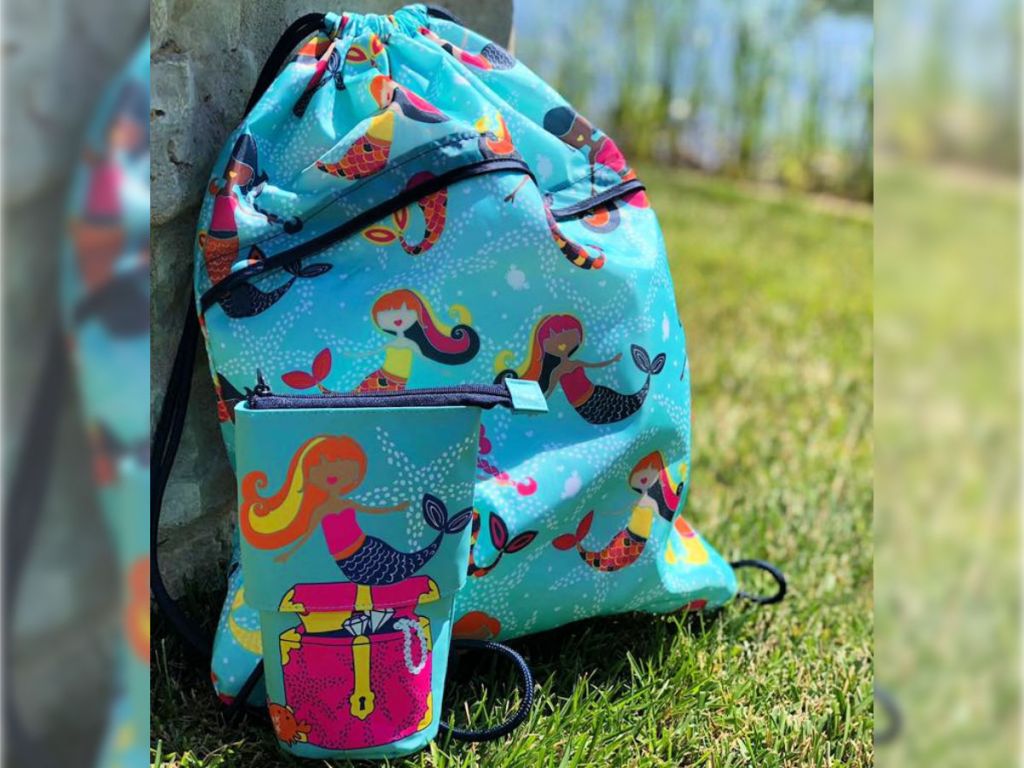 Thirty-One Cinch Sac & Hide & Peek Pouch in Mermaid Treasure on grass 