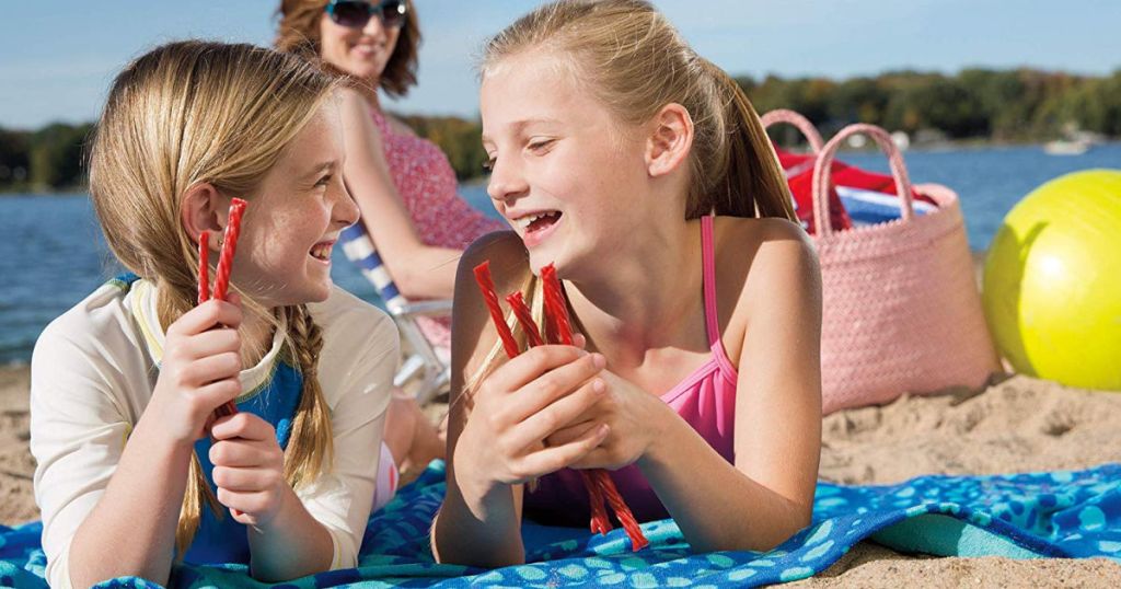 girls eating twizzlers on beach