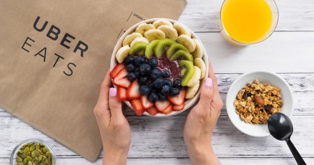 uber eats smoothie bowl with brown paper bag, granola and orange juice