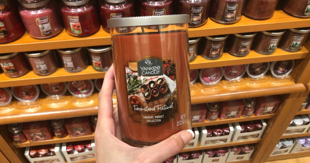 woman holding yankee tumbler candle in store