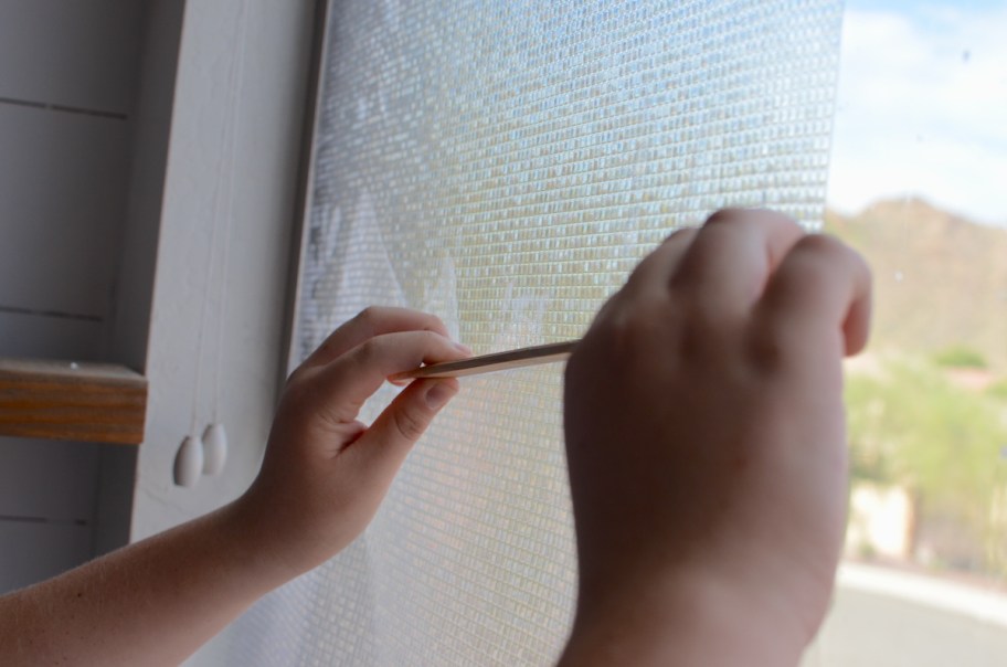 hands running ruler lengthwise down amazon privacy window film