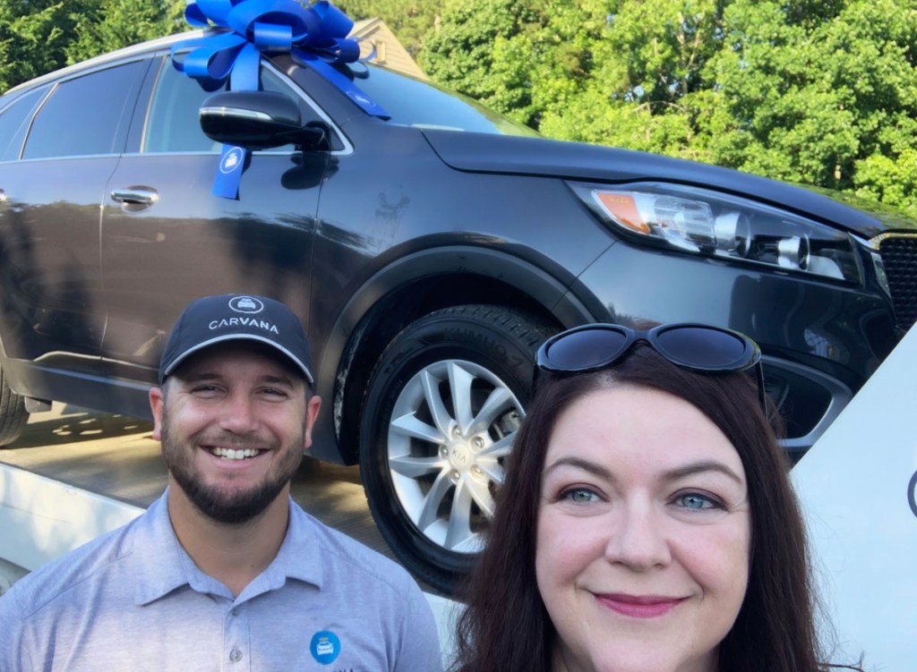 woman and man standing in front of a car at carvana dealership