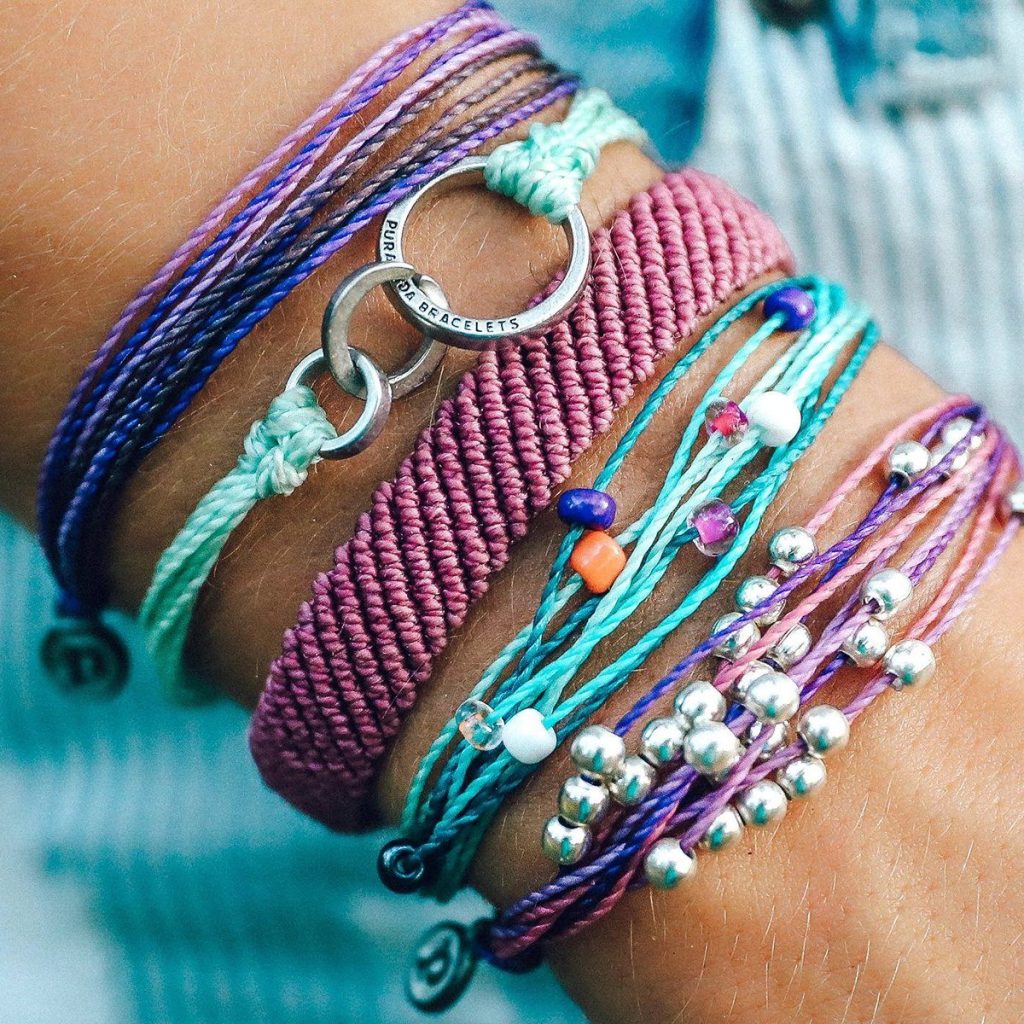 Woman wearing Pura Vida bracelets in purple and teal colors