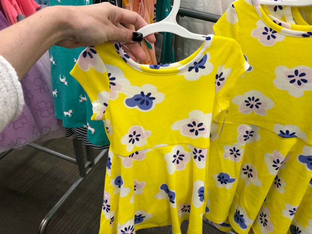 yellow dress on hanger held by hand in store