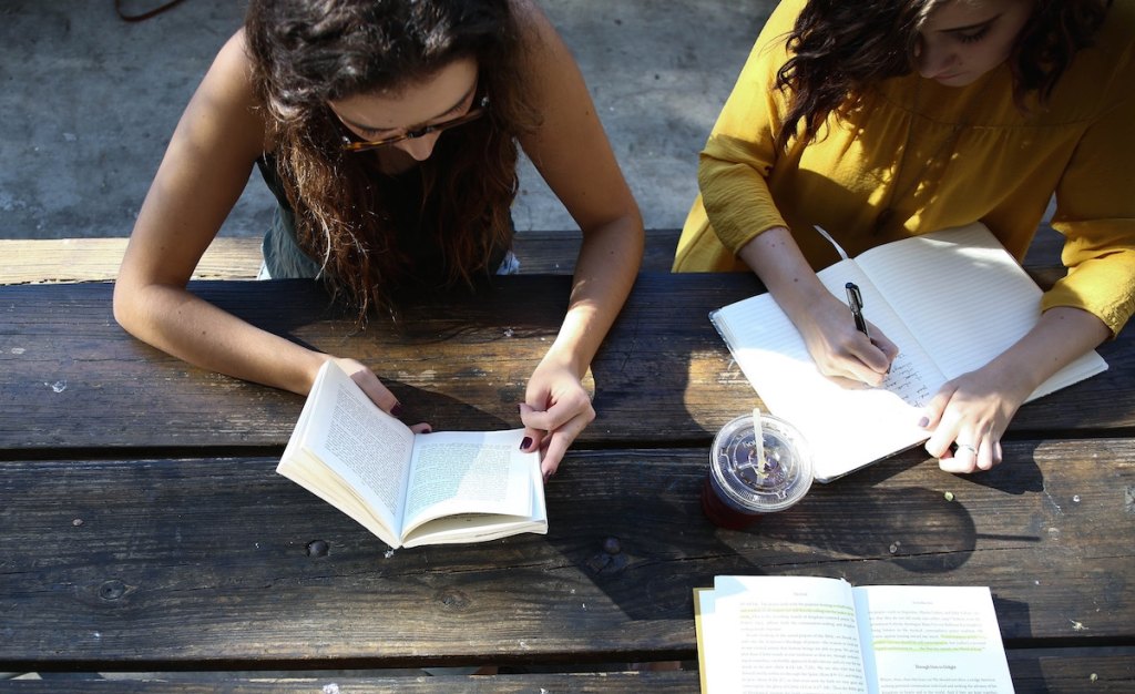 women reading and writing at picnic table