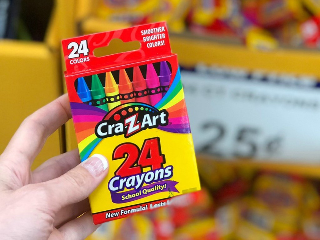 hand holding box of crayons by store display