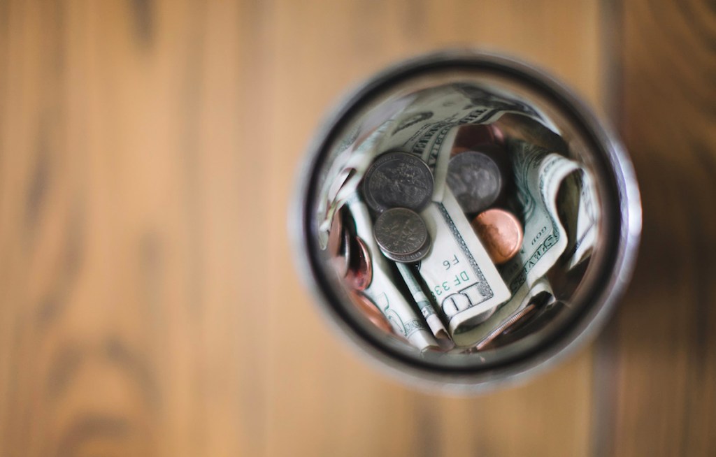 money bills and coins in glass jar