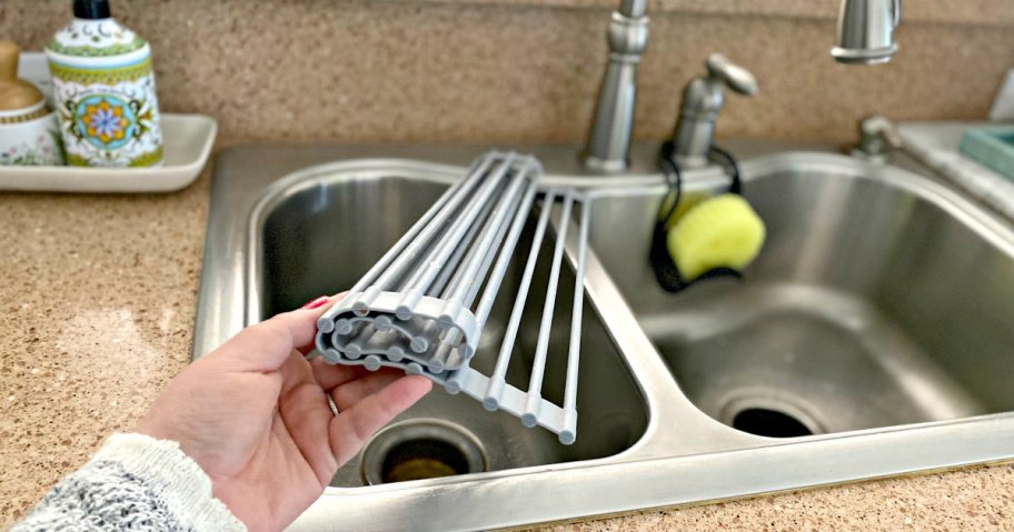 hand holding a roll-up drying mat over a sink