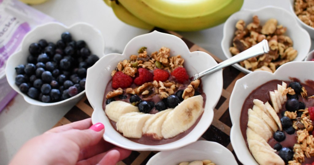 holding an acai bowl with toppings