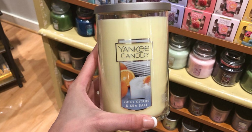 hand holding yellow candle by store display