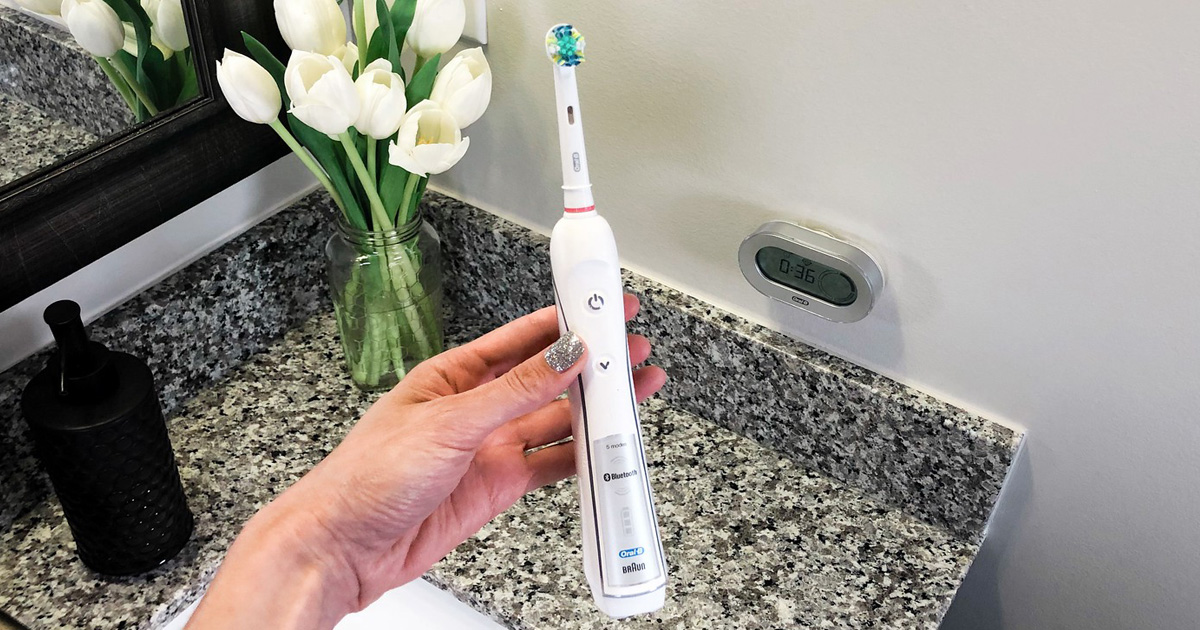 hand holding oral b 5000 electric toothbrush in bathroom