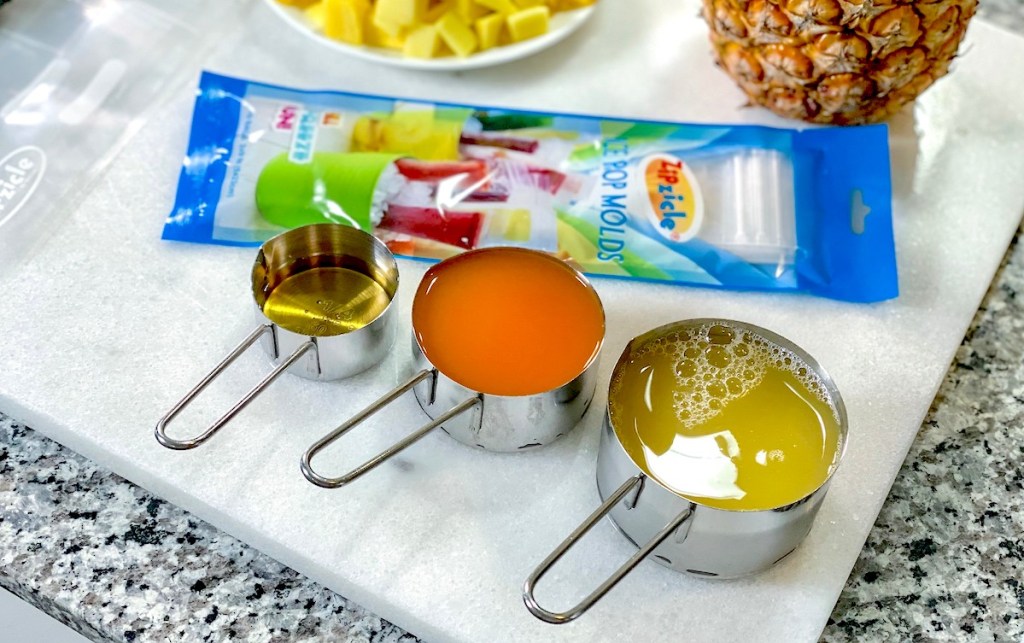 various measuring cups with different orange and yellow liquids inside