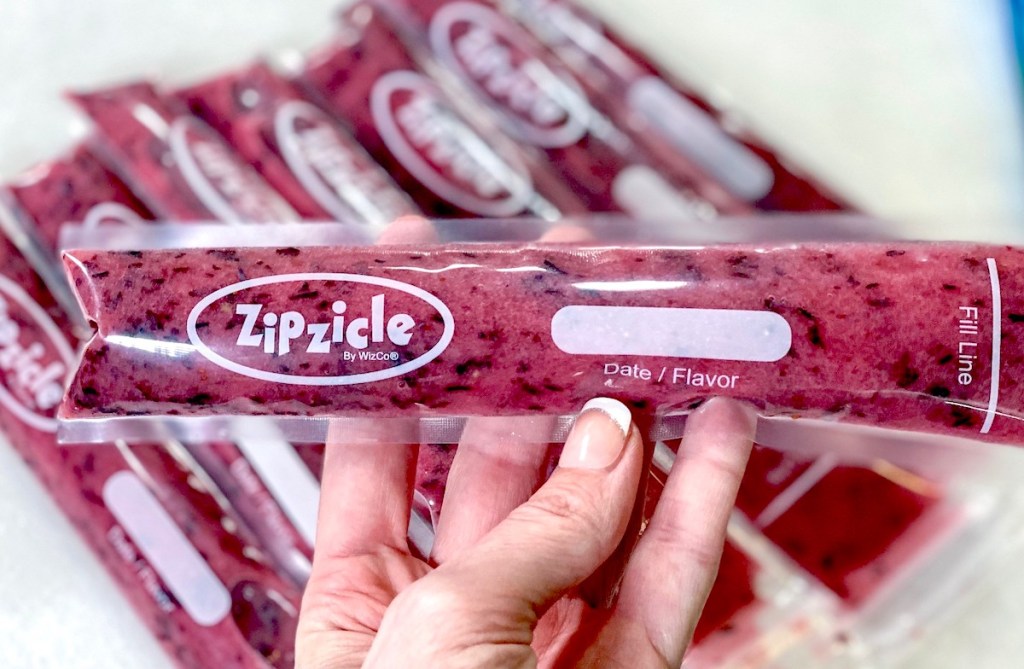 hand holding a purple frozen popsicle with others in background