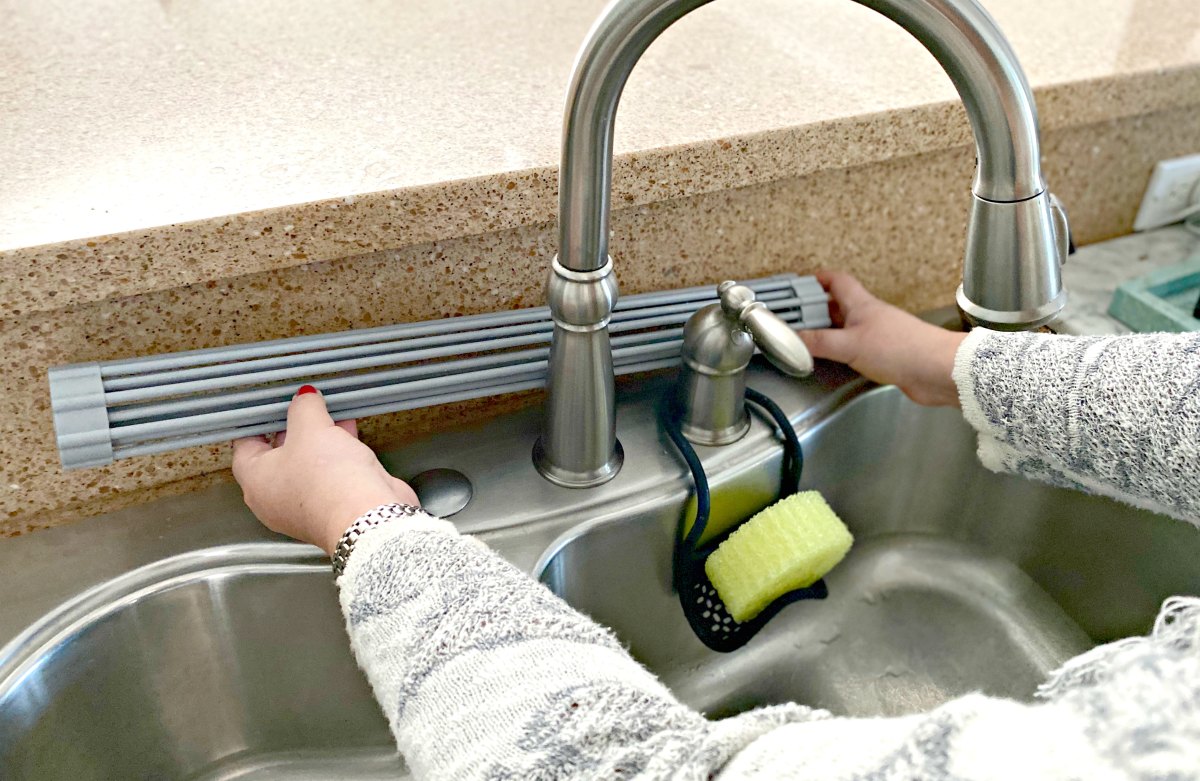 rolling up a drying mat behind the faucet