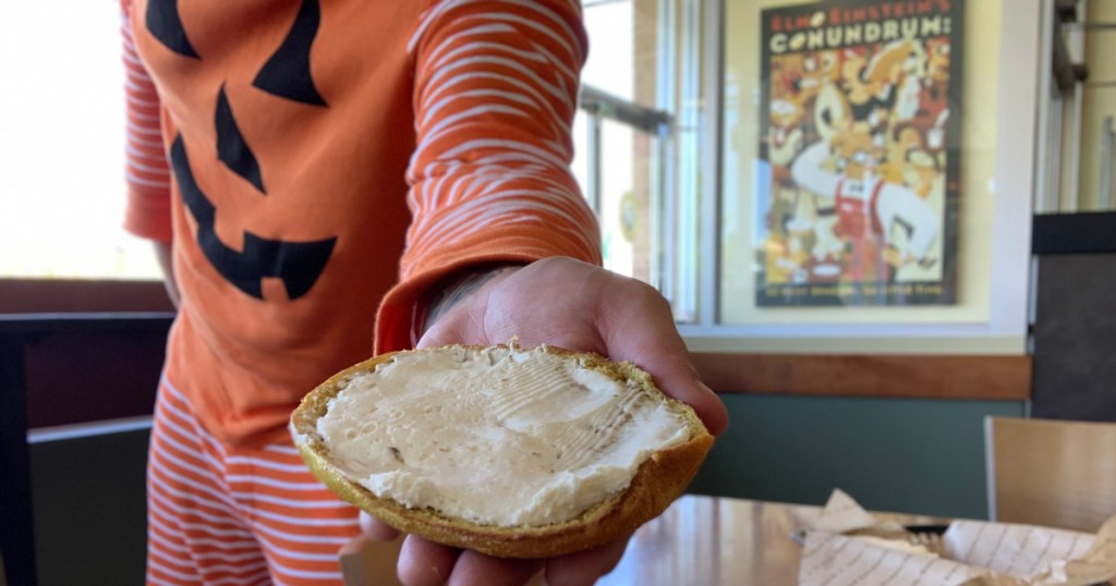 man holding bagel with cream cheese