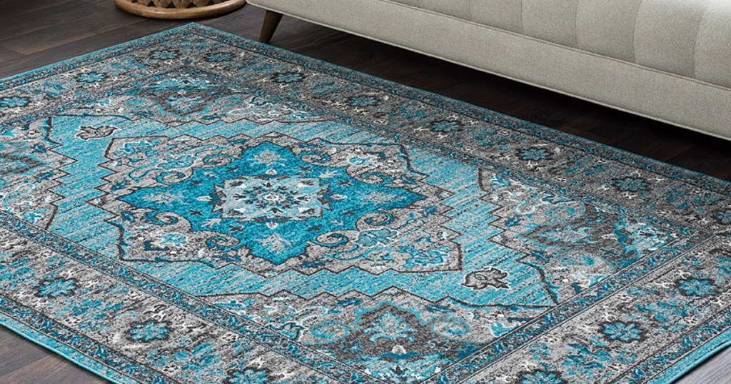 Blueish green rug on wood flooring