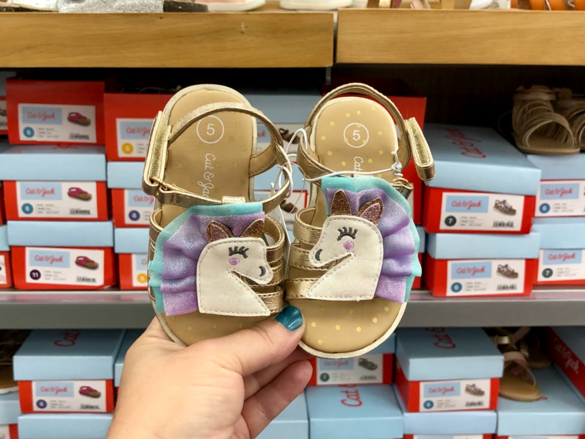 hand holding unicorn sandals in target