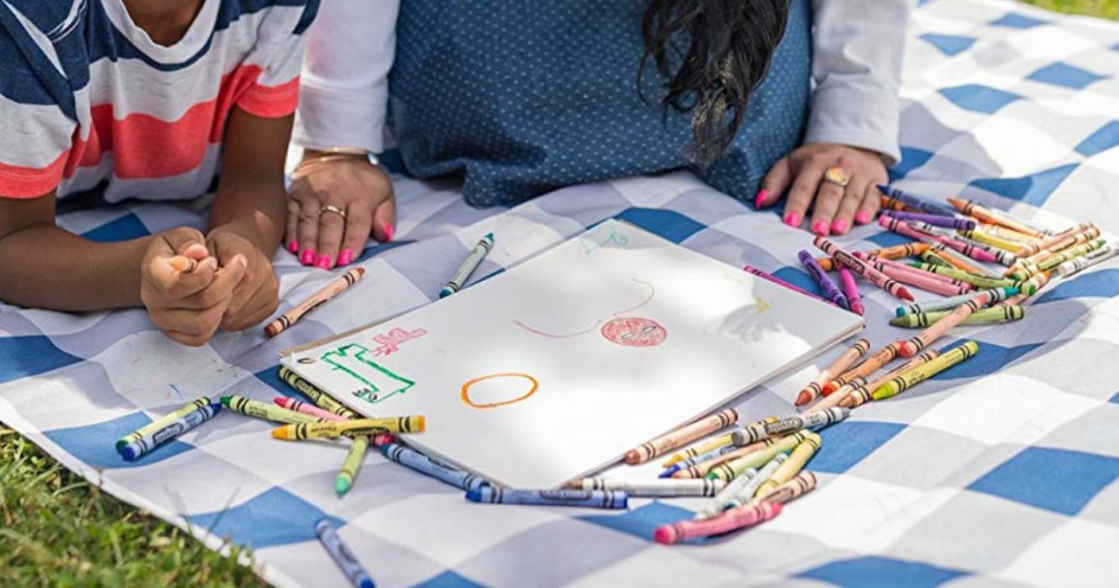 lady and a kid coloring with crayons at a picnic