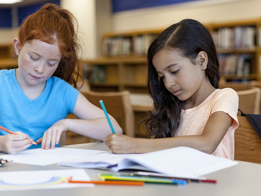 two girls coloring at a library