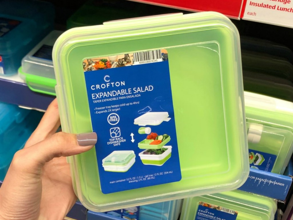 hand holding green container for lunches by store display