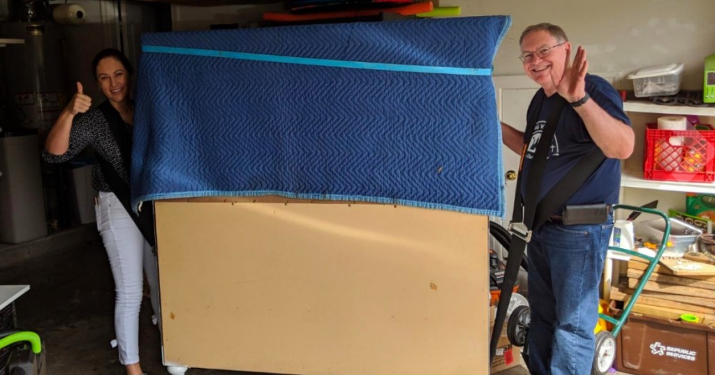 two people moving heavy furniture with moving straps