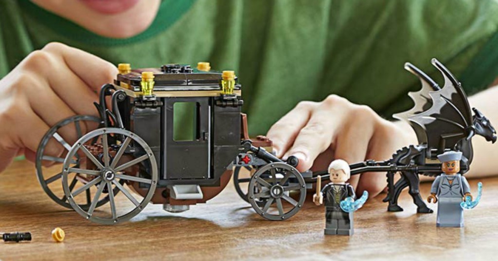 boy playing with LEGO Fantastic Beasts Grindelwald's carriage set