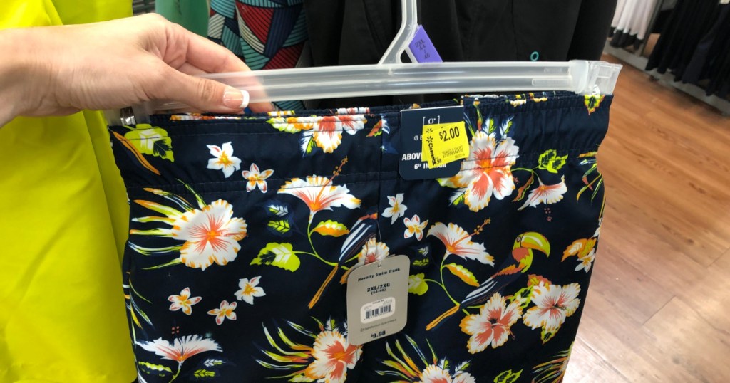 woman holding up mens swim shorts at walmart