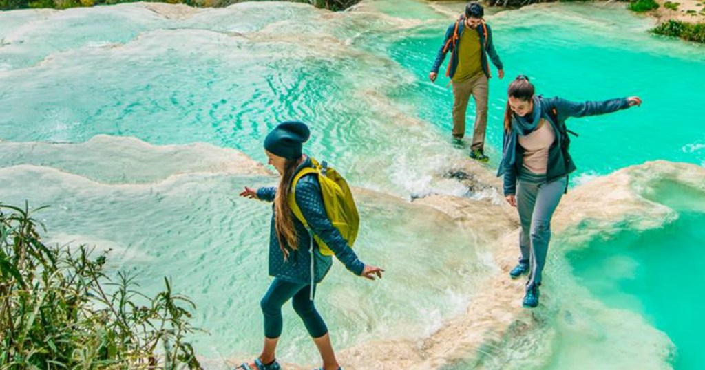 two women and a man walking across shallow water