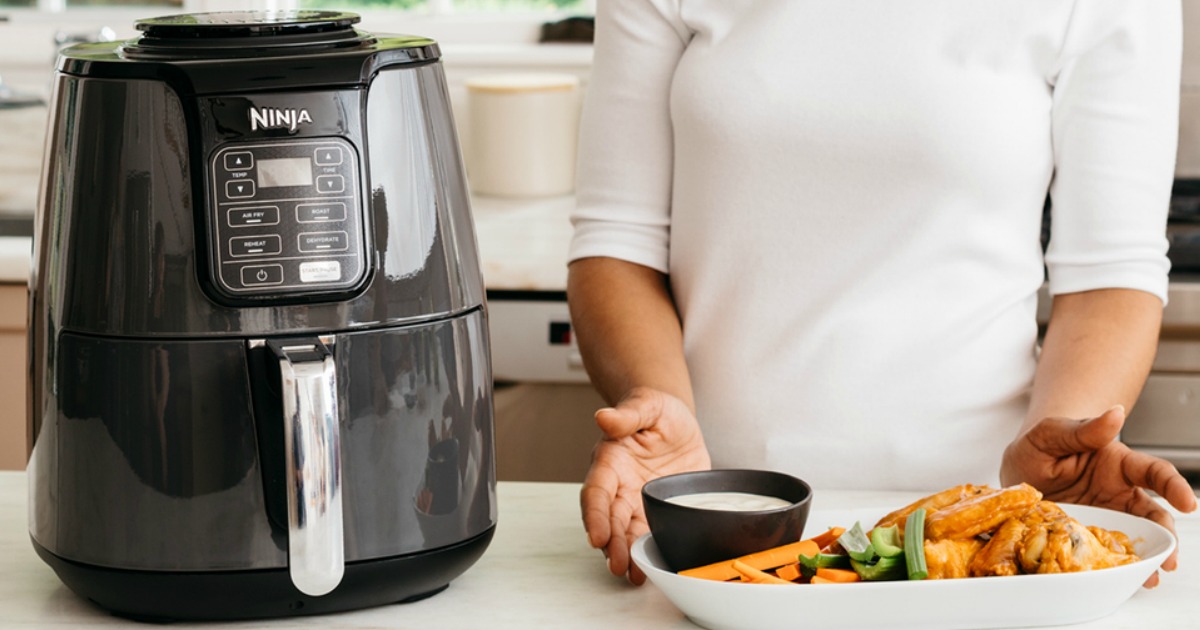 woman with plate of food standing next to a Ninja air fryer