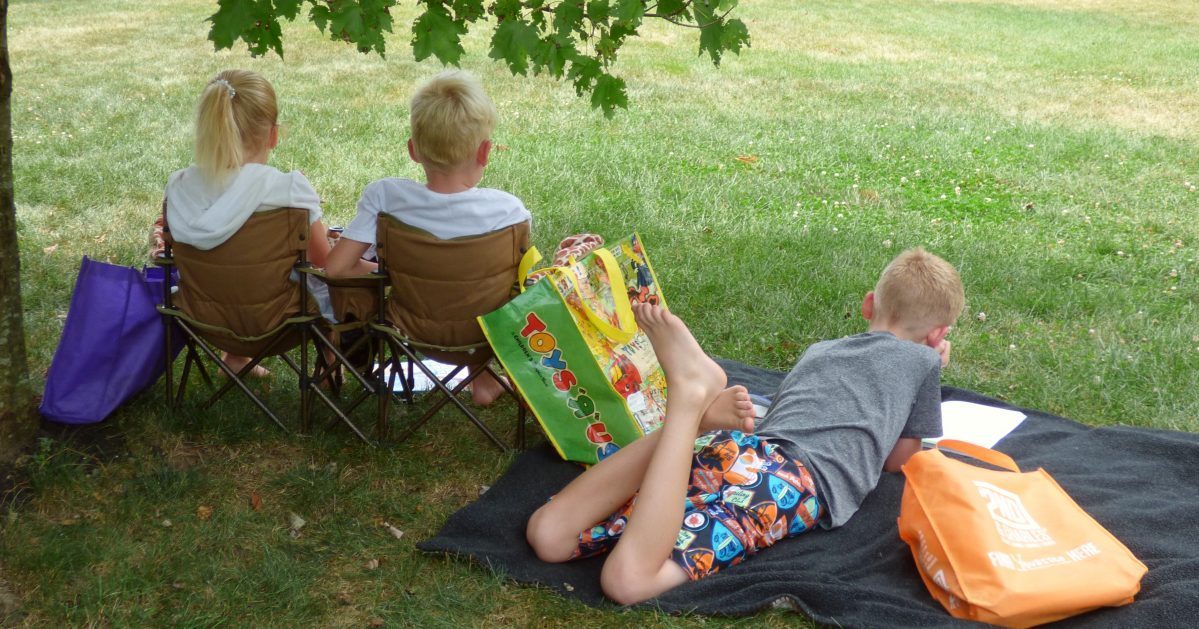 3 kids using busy bags outside