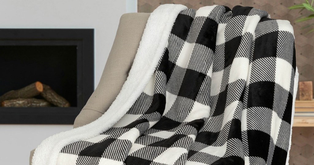 Black & White Buffalo Check Sherpa Back Throw hung over the back of a chair in front of a fireplace